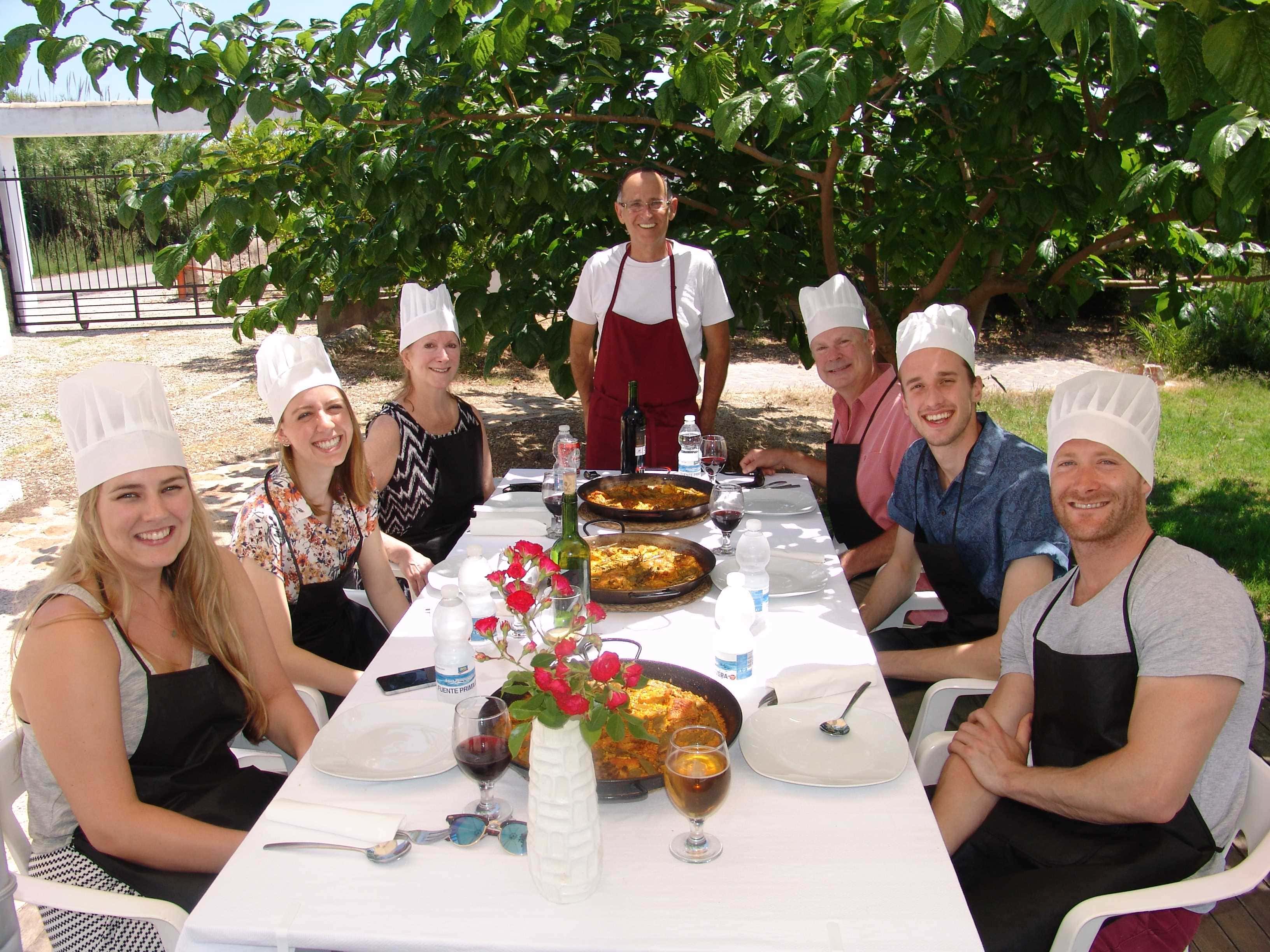 Familia cocinando paella valenciana juntos en experiencia gastronómica rural valenciana con productos de la huerta